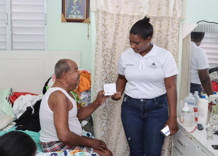 Beneficiario recibe tarjeta de bono entregada por colaboradora de Superate