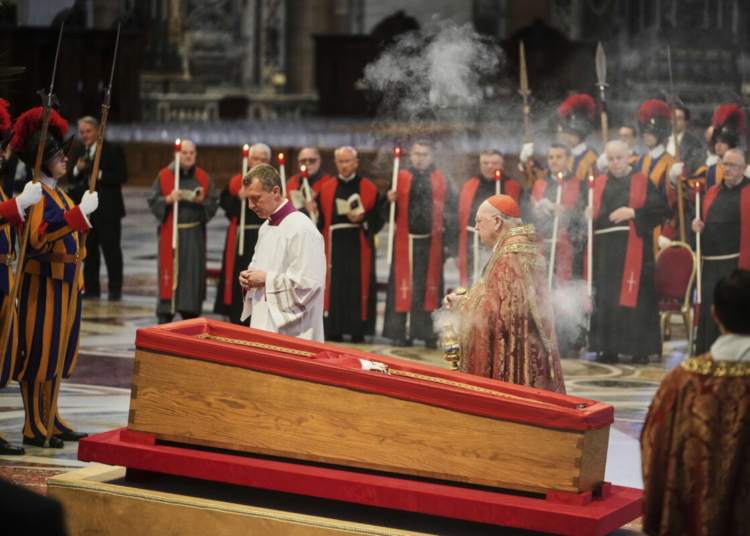 El cardenal y camarlengo del Vaticano Kevin Joseph Farrell, en el centro a la derecha, quema incienso en torno al cuerpo del papa Francisco, en la basílica de San Pedro en el Vaticano, el miércoles 23 de abril de 2025, donde estará tres días. (AP Foto/Alessandra Tarantino)