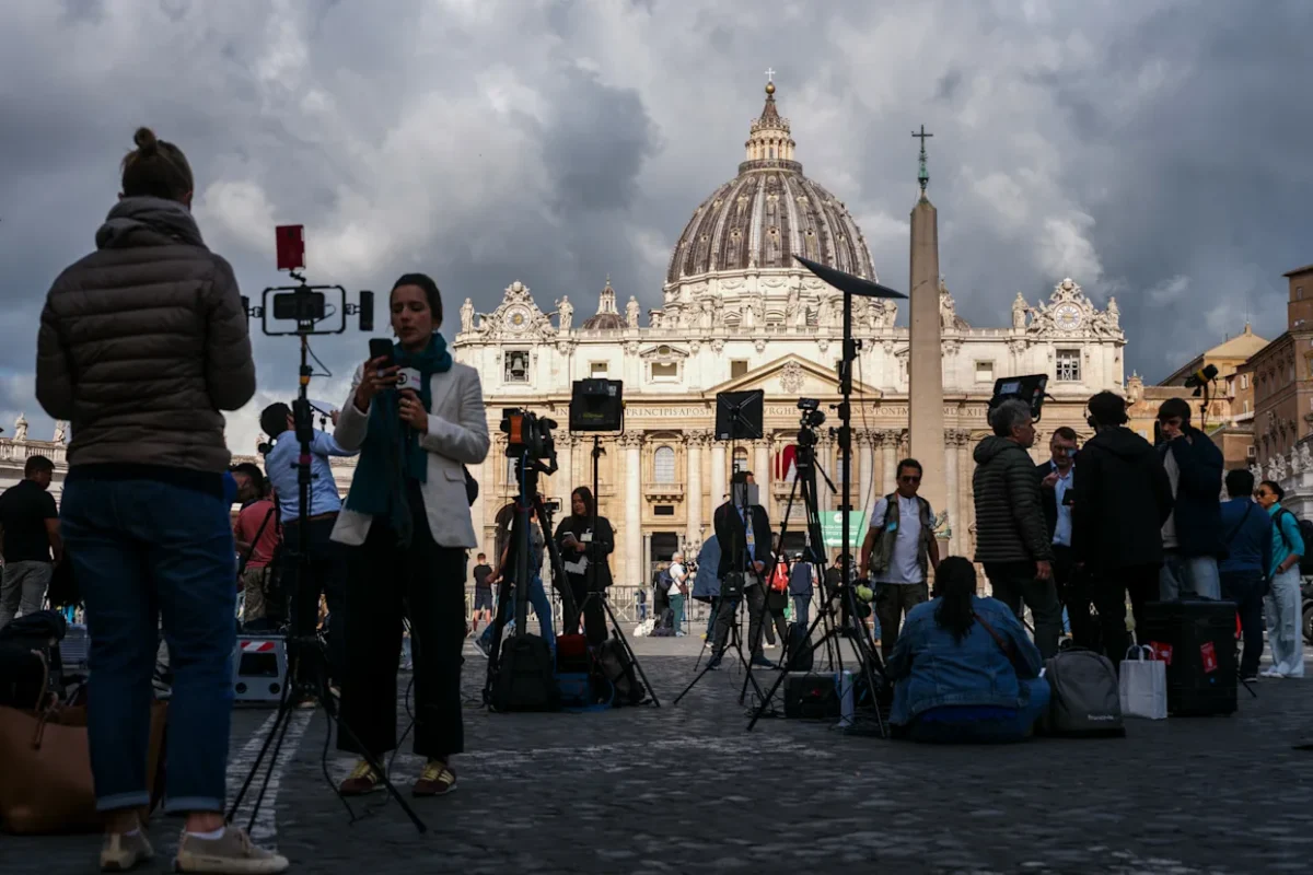 Los periodistas trabajan en la Plaza de San Pedro, con la basílica de San Pedro al fondo, antes de la segunda sesión de votación del cónclave, en el Vaticano, el 8 de mayo de 2025.