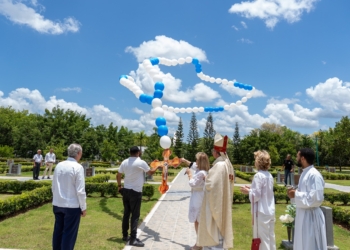 "Personas en un camposanto elevando globos al cielo durante un homenaje a las madres