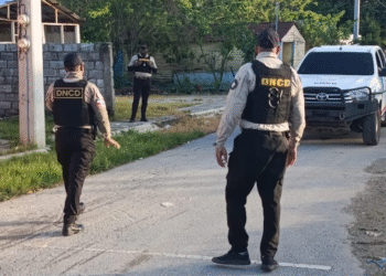 Agentes de la dncd o la policía realizando una captura, con paquetes de drogas incautadas y armas, representando un operativo antidrogas.