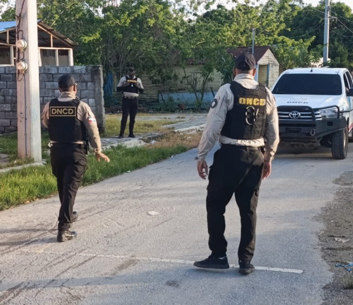 Agentes de la DNCD o la policía realizando una captura, con paquetes de drogas incautadas y armas, representando un operativo antidrogas.