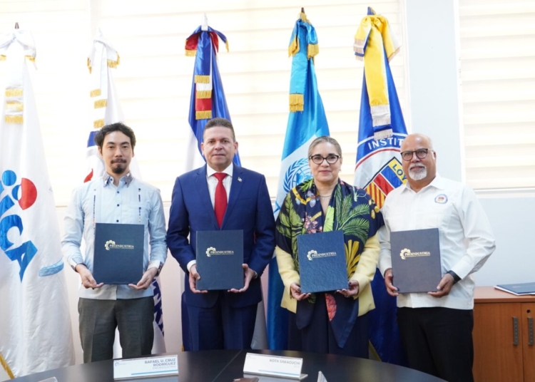 Representantes de proindustria, jica, pnud y loyola firmando un acuerdo en una mesa, con logos de las instituciones de fondo.