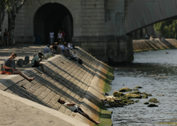 A man cools off lying on a bank of the River Seine, as a heat wave hits France, in Paris, on June 19, 2025. (Photo by Thomas SAMSON / AFP)