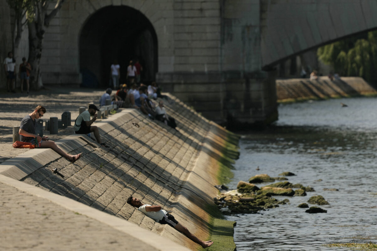 A man cools off lying on a bank of the River Seine, as a heat wave hits France, in Paris, on June 19, 2025. (Photo by Thomas SAMSON / AFP)