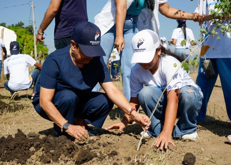 La doctora Carmen Alicia Quijano, presidente del Voluntariado Banreservas, siembra árbol junto a su nieta.
