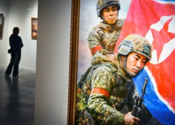 Un visitante camina junto a la pintura "Los hijos de la patria" de Kim Yeong Chan durante la exposición de arte norcoreano en Moscú, el 2 de octubre de 2025 (Alexander NEMENOV)