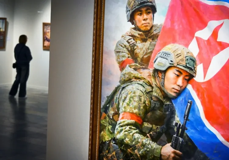 Un visitante camina junto a la pintura "Los hijos de la patria" de Kim Yeong Chan durante la exposición de arte norcoreano en Moscú, el 2 de octubre de 2025 (Alexander NEMENOV)