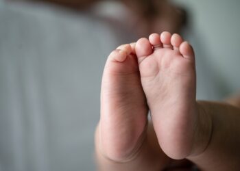 Baby feet in white bed. Selective focus.