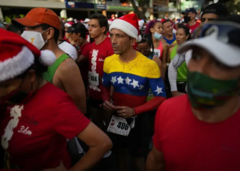 With the colors of the Venezuelan flag on his chest, Runner Juan Carlos Vargas waits for the start of the Santa Run 10K race in Caracas, Venezuela, Sunday, Dec. 19, 2021. This is the first Santa Run since the beginning of the pandemic. (AP Photo/Ariana Cubillos)