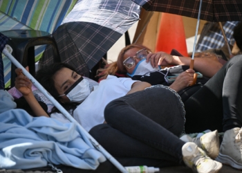 Relatives of a political prisoner lie on the ground during a protest outside the Bolivarian National Police (PNB) Zona 7 prison in Caracas on February 14, 2026. About a dozen relatives of political prisoners began a hunger strike outside a prison facility in Caracas on February 14, AFP observed, after Parliament postponed the approval of a historic amnesty bill two days earlier. (Photo by Federico PARRA / AFP)